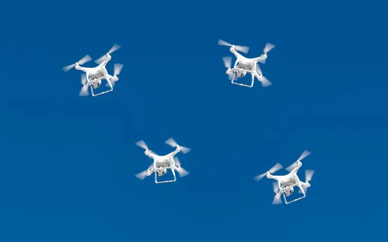 A drone swarm flying in a blue sky