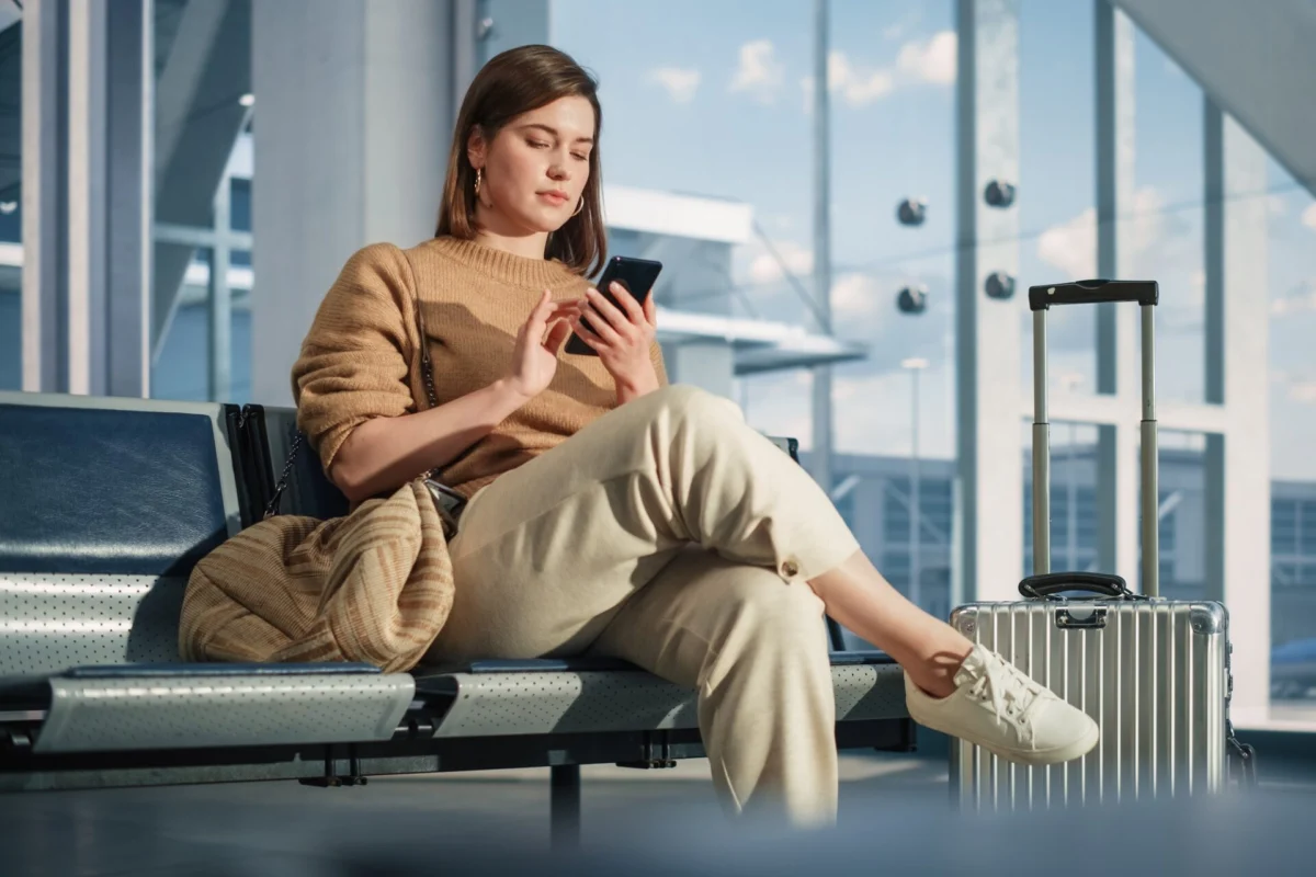 Female passenger scrolling her phone in an airport terminal Female passenger scrolling her phone in an airport terminal