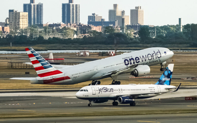 American Airlines Boeing 777 taking off from John F. Kennedy International Airport with the jetBlue Airbus A320 taxing behind it
