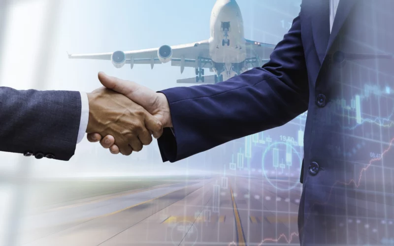 Two men shaking hands by a plane