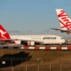 Qantas Airbus A320 taxiing behind Virgin Australia aircraft