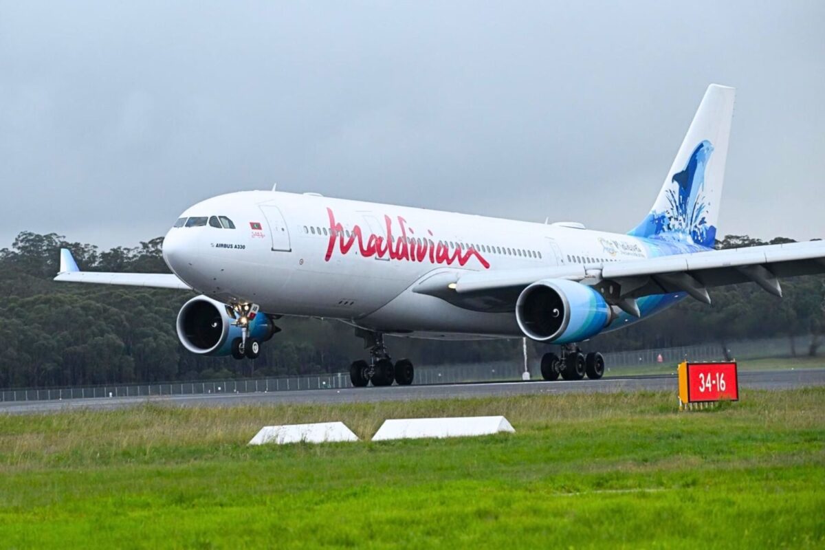Maldives A330 aircraft on a runway with landing gear down and a blue tinted tail design visible behind trees