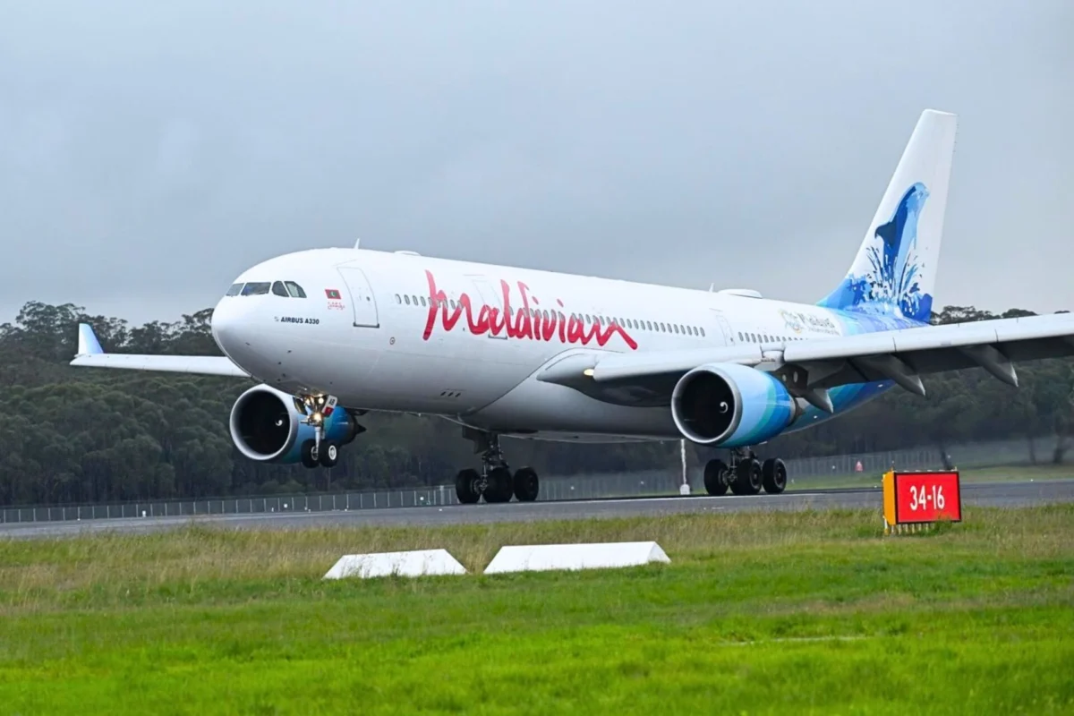 Maldivian A330 200 Maldives A330 aircraft on a runway with landing gear down and a blue tinted tail design visible behind trees