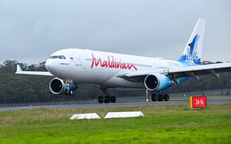 Maldivian A330 200 Maldives A330 aircraft on a runway with landing gear down and a blue tinted tail design visible behind trees