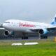 Maldives A330 aircraft on a runway with landing gear down and a blue tinted tail design visible behind trees