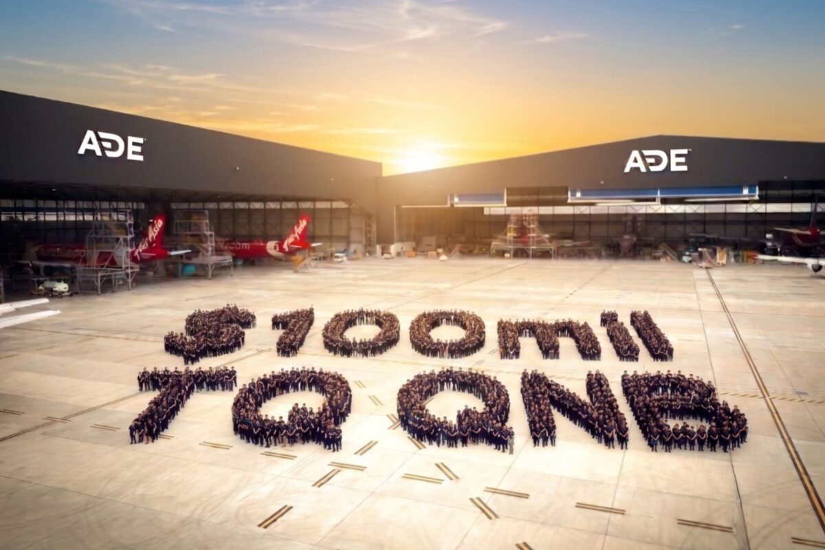 Aerial view of an airport apron at sunset with ADE hangars and several aircraft hundreds of people form a large number on the tarmac