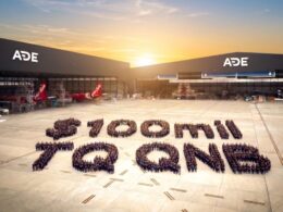 Aerial view of an airport apron at sunset with ADE hangars and several aircraft hundreds of people form a large number on the tarmac