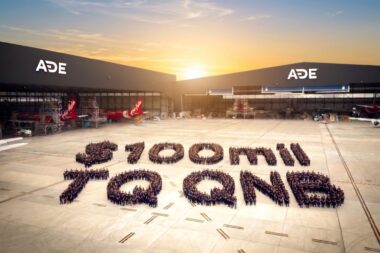 Aerial view of an airport apron at sunset with ADE hangars and several aircraft hundreds of people form a large number on the tarmac