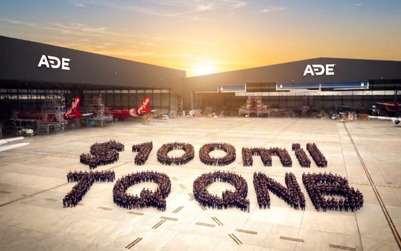 Untitled design 13 Aerial view of an airport apron at sunset with ADE hangars and several aircraft hundreds of people form a large number on the tarmac