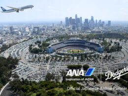 Aerial view of downtown Los Angeles with Dodger Stadium in the foreground and an ANA airplane taking off in the blue sky above