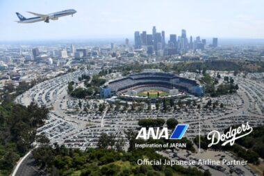 Aerial view of downtown Los Angeles with Dodger Stadium in the foreground and an ANA airplane taking off in the blue sky above