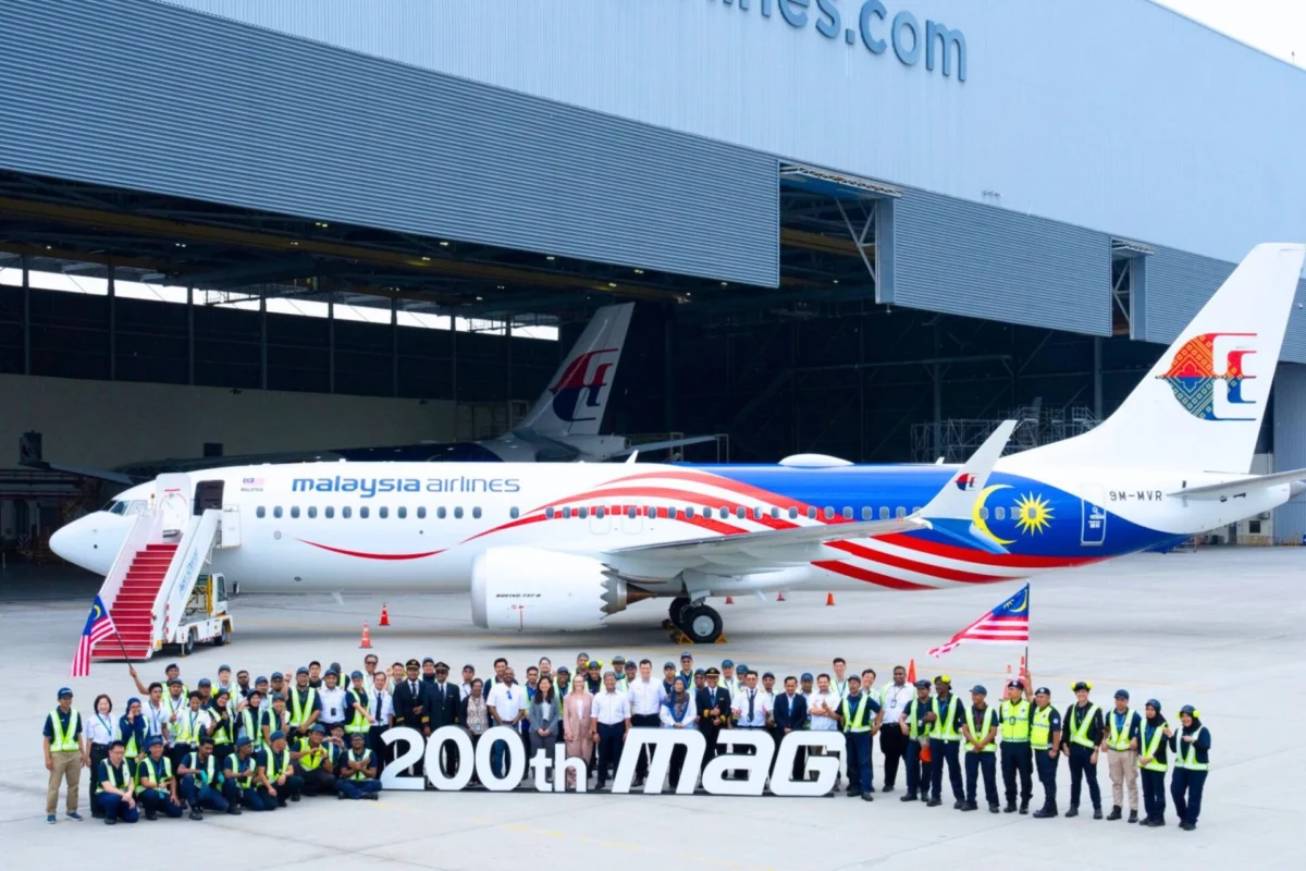 Untitled design 18 Group of Malaysia Airlines staff and engineers posing with a colorful jet inside a hangar in front of a large 200th MAG banner