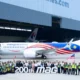 Group of Malaysia Airlines staff and engineers posing with a colorful jet inside a hangar in front of a large 200th MAG banner