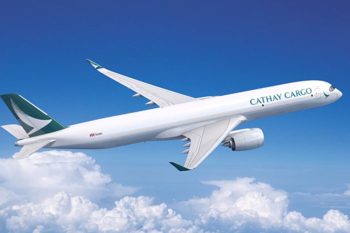 Cathay Cargo airplane in flight with a teal logo on the tail soaring above white clouds in a bright blue sky