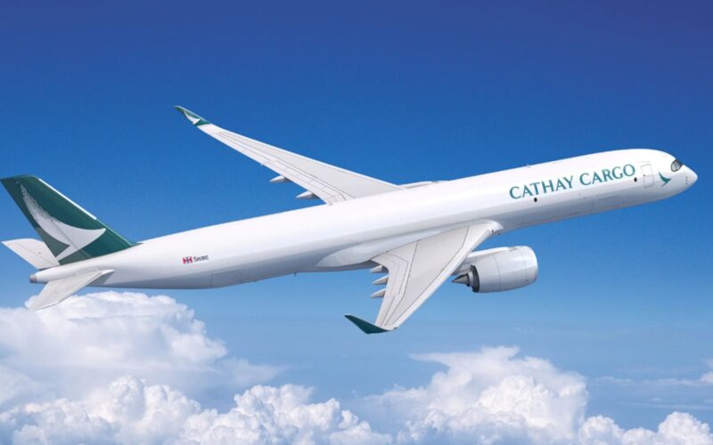 Cathay A350F Cathay Cargo airplane in flight with a teal logo on the tail soaring above white clouds in a bright blue sky
