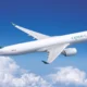 Cathay Cargo airplane in flight with a teal logo on the tail soaring above white clouds in a bright blue sky