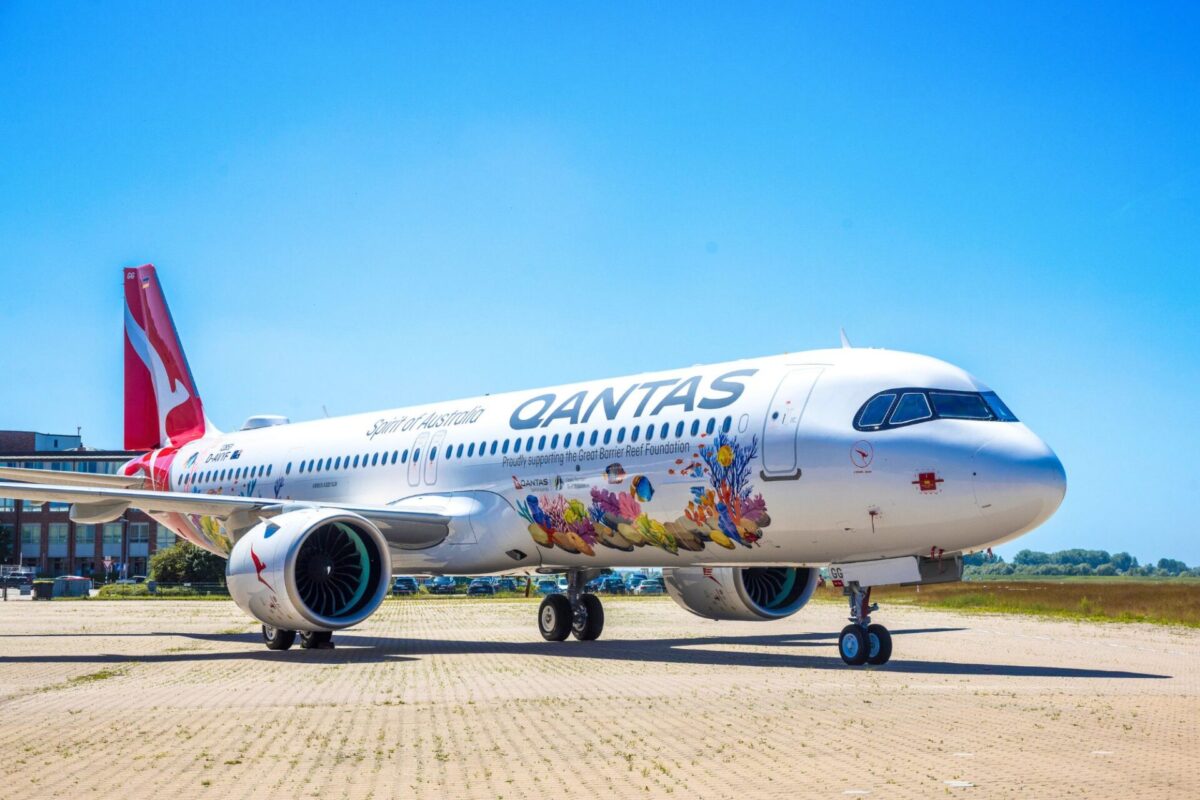 Qantas A321XLR Great Barrier Reef livery Qantas airplane parked on a tarmac with vibrant coral reef artwork along its fuselage and a bright blue sky above
