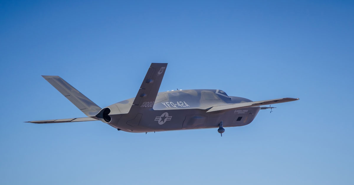 YFQ 42A Collaborative Combat Aircraft B 2 Spirit stealth bomber in flight underside view with landing gear down against a clear blue sky