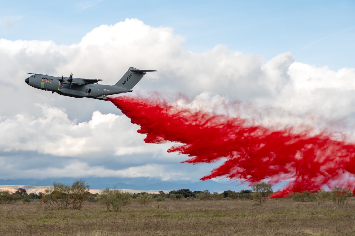 a400m firefighter image Military transport airplane releasing bright red smoke trail over an open field