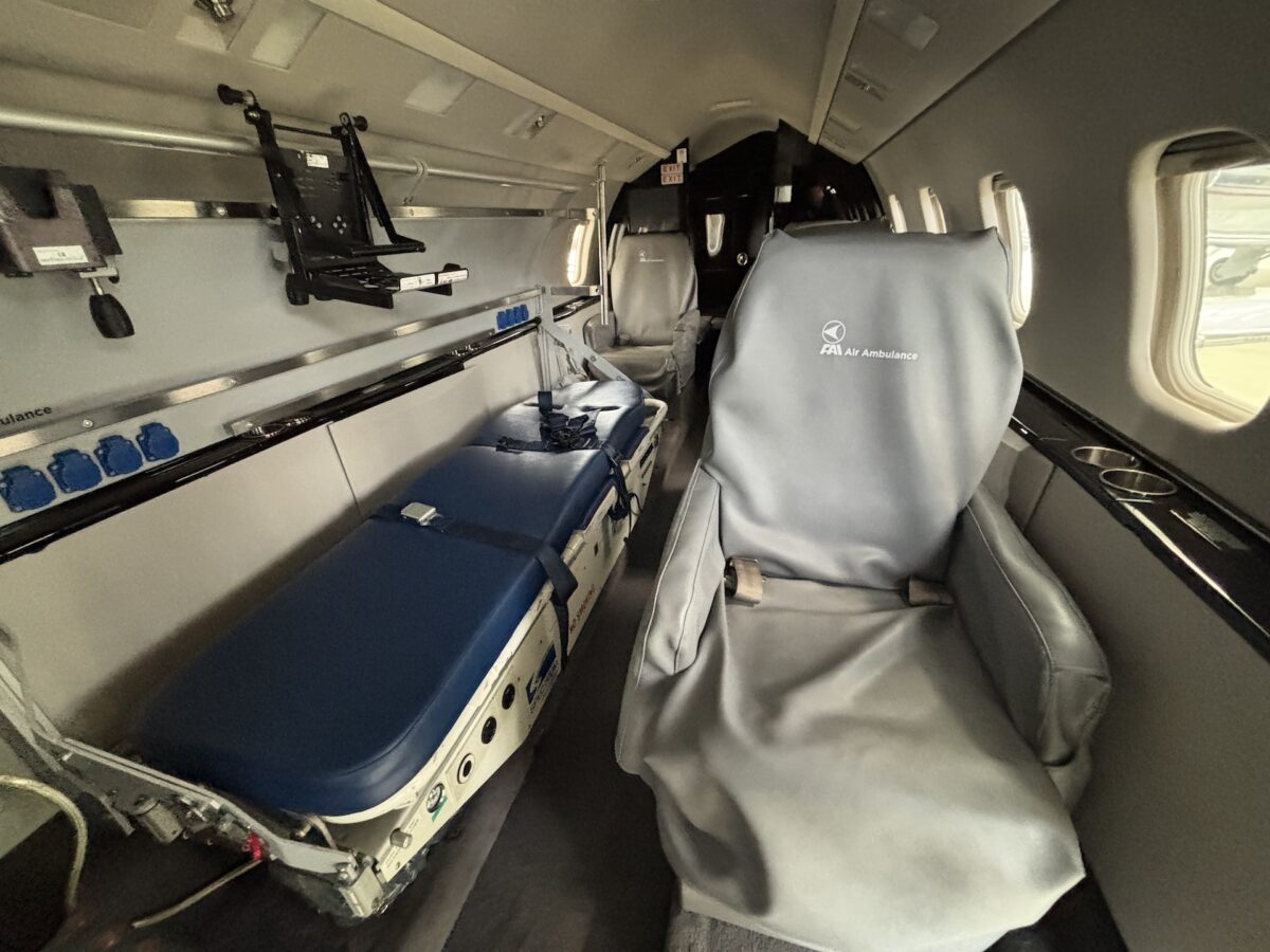 Inside an air ambulance with a padded patient cot and medical equipment along the wall ready for transport