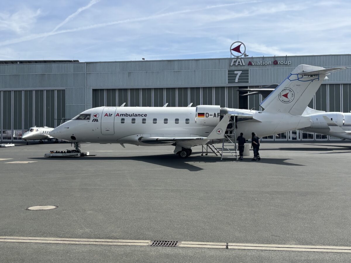 FAI Air Ambulance jet parked on the apron in front of a hangar with crew nearby