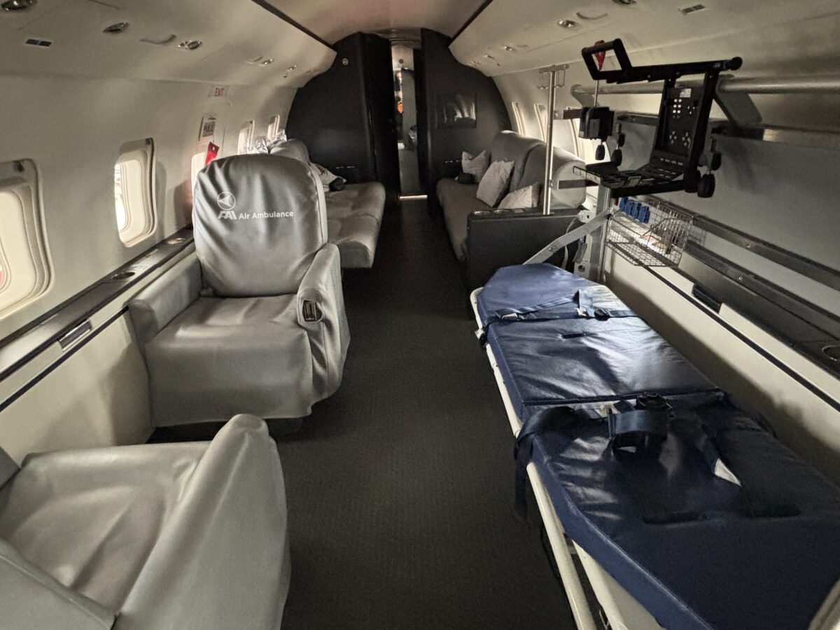 Interior of an air ambulance with a blue patient stretcher on the right and gray seats along the walls