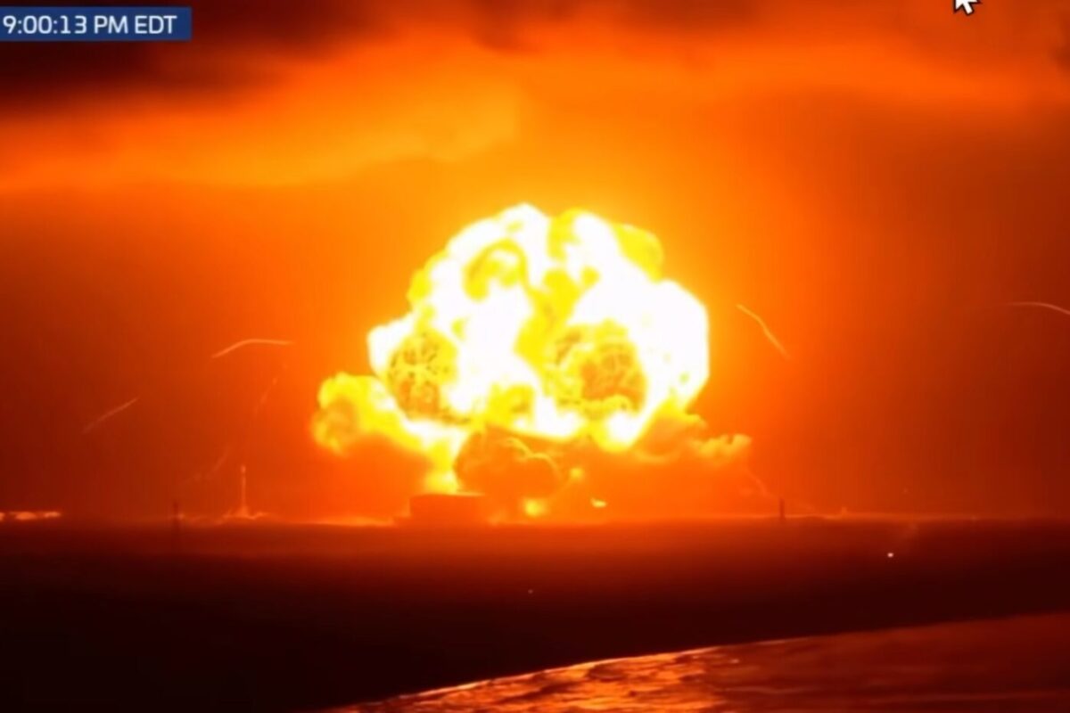 blueoriginexplosion Massive orange fireball explosion on water at night with embers and smoke rising above the horizon