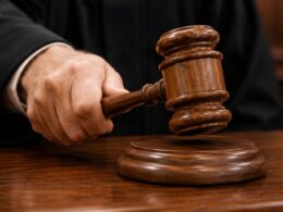 Judges wooden gavel about to strike a sound block on a courtroom desk signaling a ruling