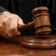 Judges wooden gavel about to strike a sound block on a courtroom desk signaling a ruling