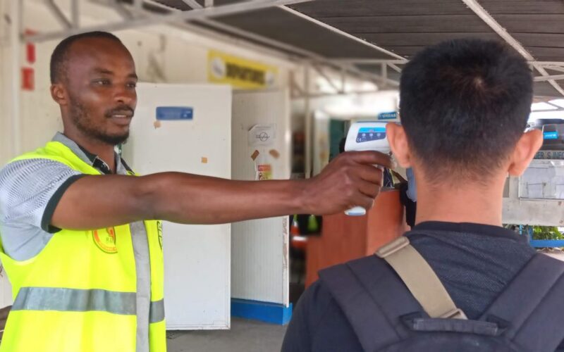 goma airport drc ebola tempreature check1f51993d9c604c1290f83b48379c97d3 A worker in a bright safety vest uses a handheld thermometer to check a persons temperature at a checkpoint outside a facility