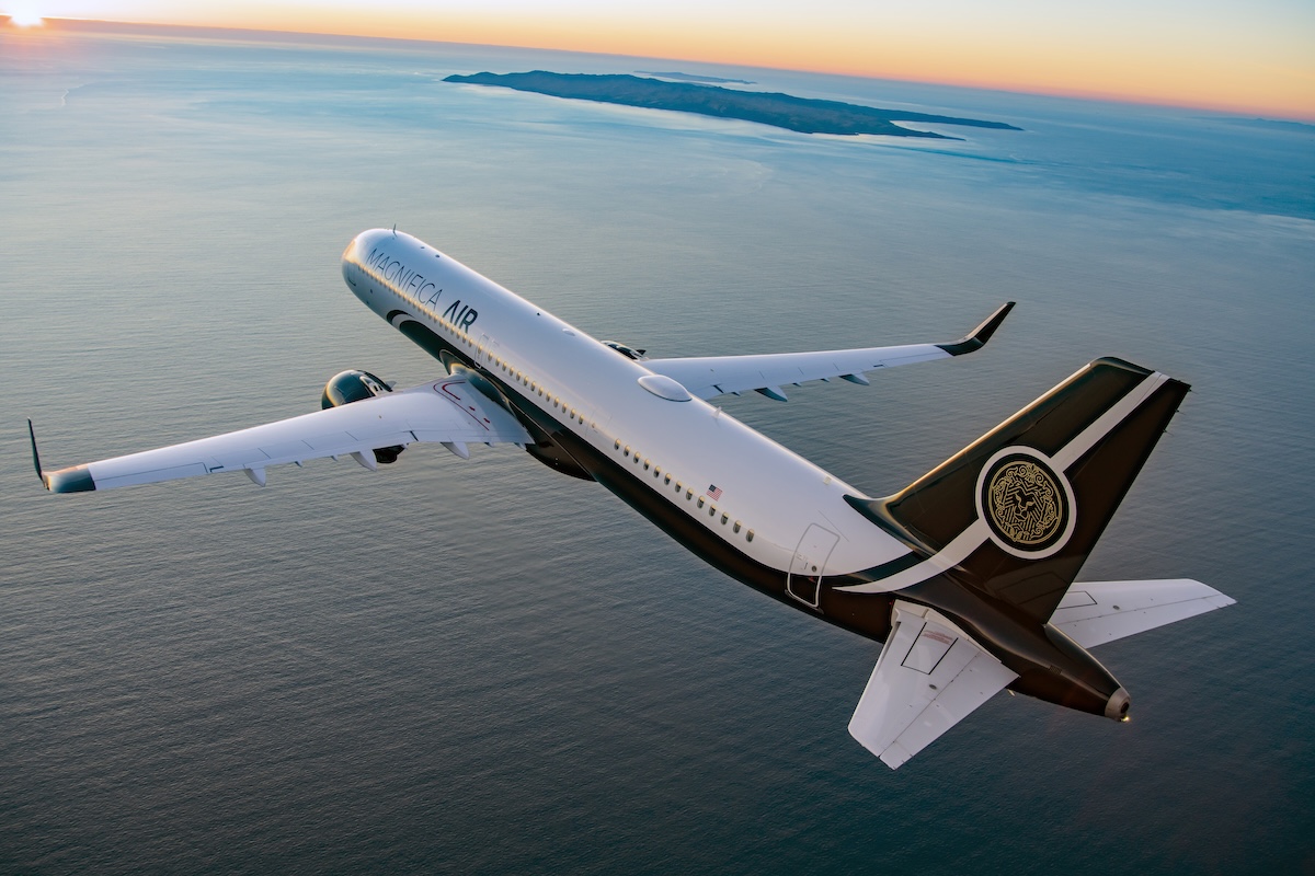 magnifica air rendering 2 White private jet with Magnifica Air branding banks over the calm ocean at sunset with distant islands on the horizon