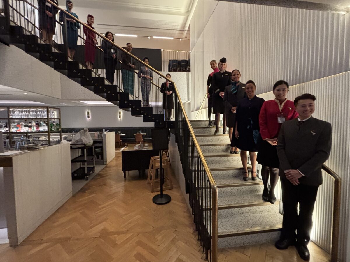 oneworld crew Staff members in uniform stand along a curved staircase in a modern interior smiling at the camera