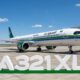 Saudia Airbus A321XLR parked at the gate with a green and blue stripe livery under a blue skyFront right view of a Saudia A321XLR at the jet bridge white fuselage with green tail and logoLarge 1st A321XLR signage on the ground in front of the parked airliner on the tarmac