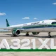Saudia Airbus A321XLR parked at the gate with a green and blue stripe livery under a blue skyFront right view of a Saudia A321XLR at the jet bridge white fuselage with green tail and logoLarge 1st A321XLR signage on the ground in front of the parked airliner on the tarmac
