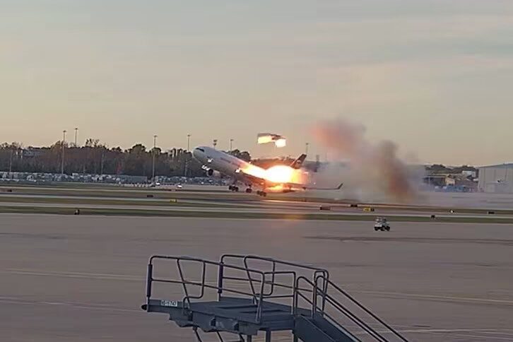 ups Large passenger jet lifting off the runway with a bright exhaust flame and smoky plume trailing behind at sunset