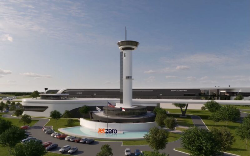 JetZero NC factory Rendering of Jet Zero facility with a tall controltower structure and circular base surrounded by a curved white building and parking lot with cars and trees