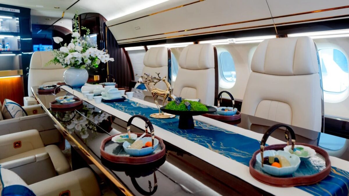 20260625094459 8180 Luxurious private jet cabin with a long glossy dining table set for a meal white leather seats and flower centerpiece