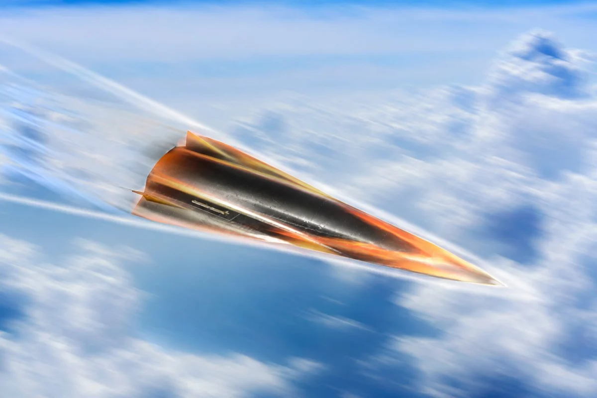 Orange and black jet like aircraft speeding to the right through a blue sky with wispy clouds motion blur