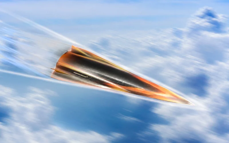 Orange and black jet like aircraft speeding to the right through a blue sky with wispy clouds motion blur