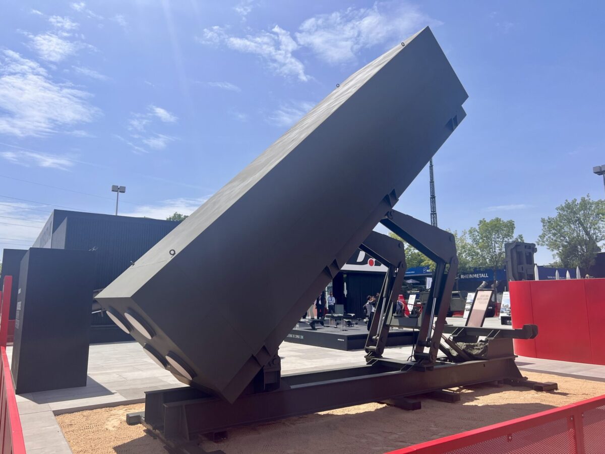 A launcher module displayed in firing position on MBDAs stand at Eurosatory 2026 Credit AeroTime Massive dark gray industrial equipment on a raised platform outdoors angled toward the sky with a few visitors nearby