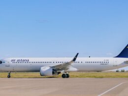Air Astana passenger jet on a taxiway with a blue sky and a blue tailed logo