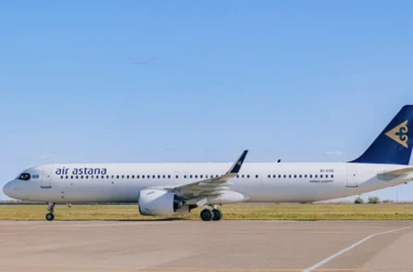 Air Astana passenger jet on a taxiway with a blue sky and a blue tailed logo