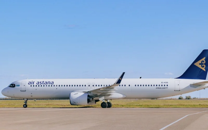 Air Astana passenger jet on a taxiway with a blue sky and a blue tailed logo