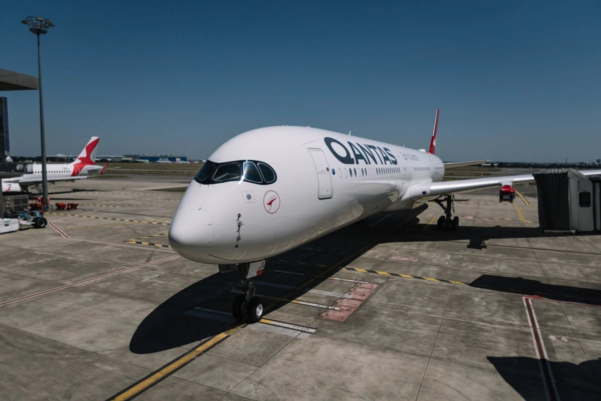 Qantas airliner parked at the gate on a sunny day with a jet bridge nearby