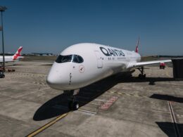 Qantas airliner parked at the gate on a sunny day with a jet bridge nearby
