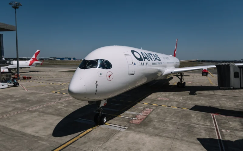 Qantas airliner parked at the gate on a sunny day with a jet bridge nearby