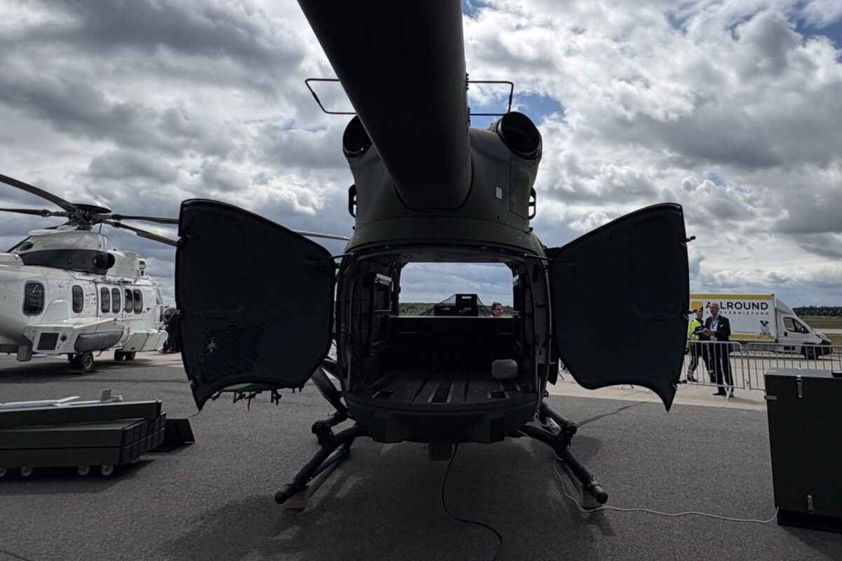 Airbus U145 uncrewed helicopter cargo bay Front view of a military helicopter with its rear cargo doors open exposing the dark interior on a tarmac with another helicopter nearby