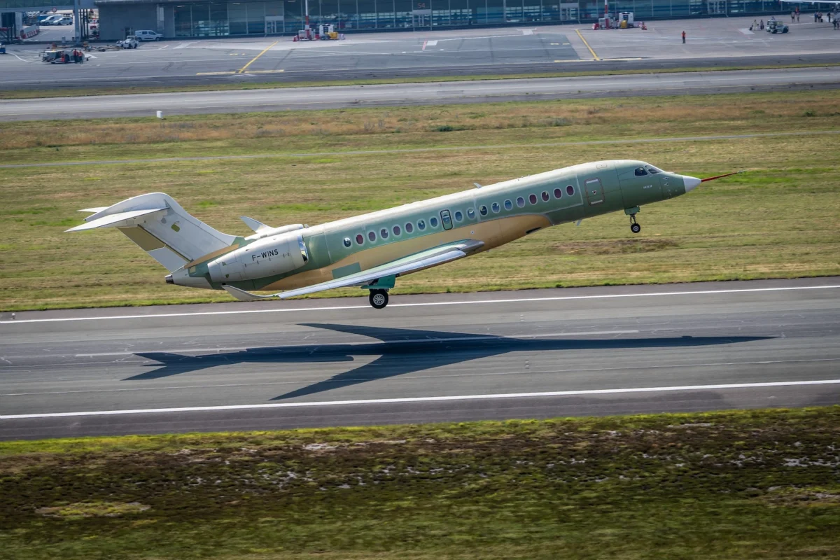 © Dassault Aviation A Pecchi © Dassault Aviation A Pecchi Green private jet taking off on a runway at an airport with grassy field and terminal buildings in the background tail number F WINS
