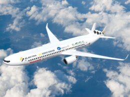 White passenger jet with sponsor logos flying above a cloudy blue sky