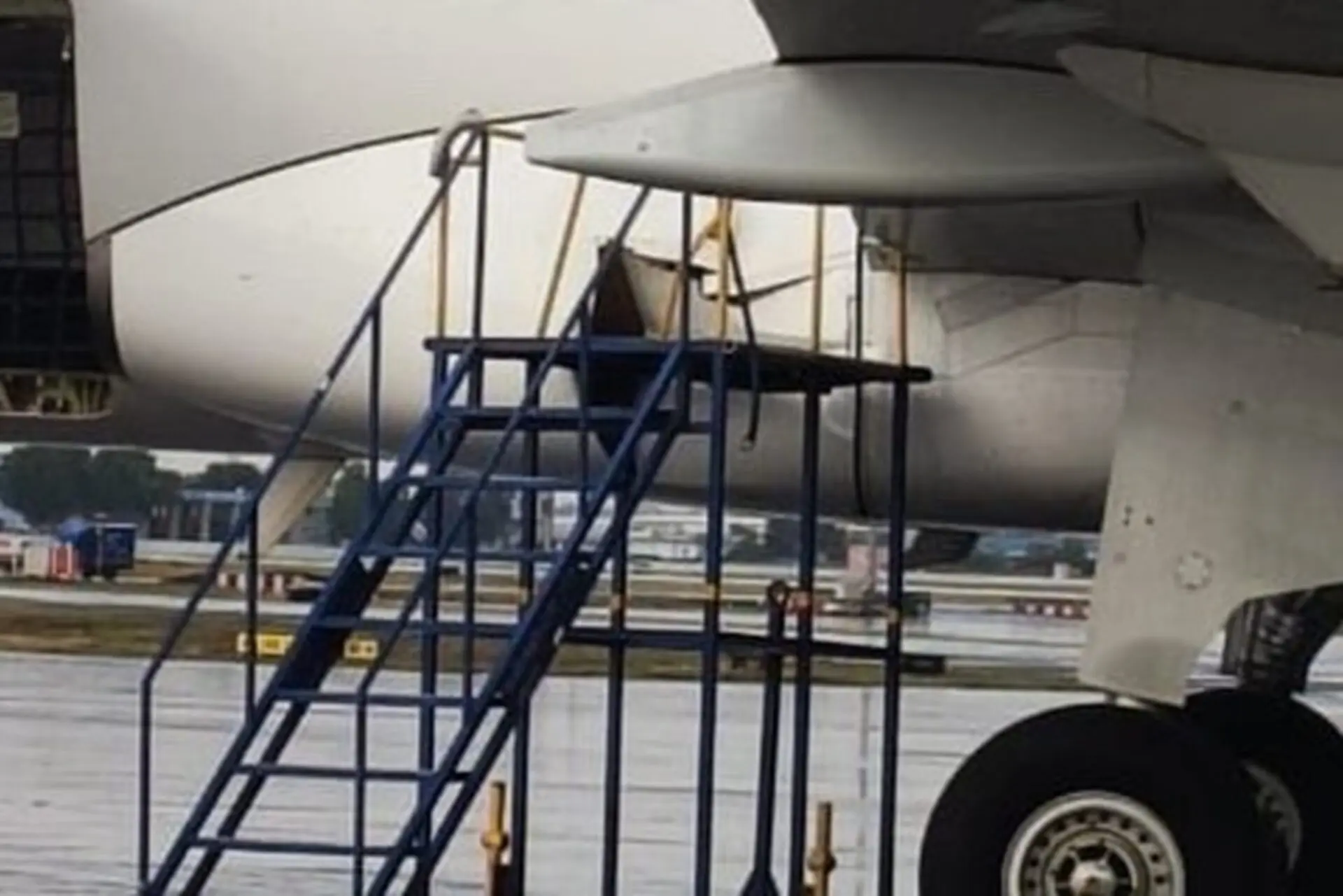 Close up view of a jet engine nacelle with blue boarding stairs parked at the wing on the tarmac